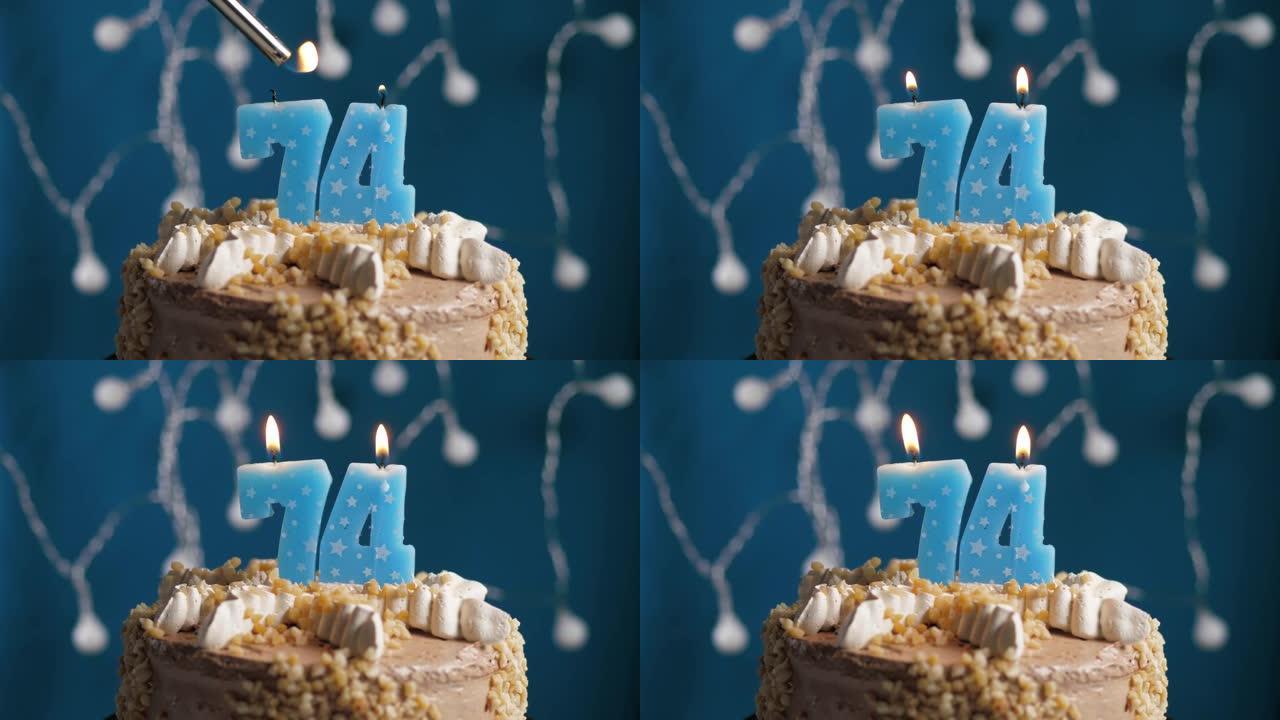 蓝色背景上有74号蜡烛的生日蛋糕。蜡烛着火了。慢动作和特写视图