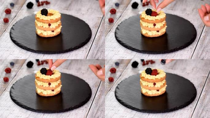 糕点厨师用奶油冻和浆果制作法国Mille Feuille。法式甜点千层酥和奶油。