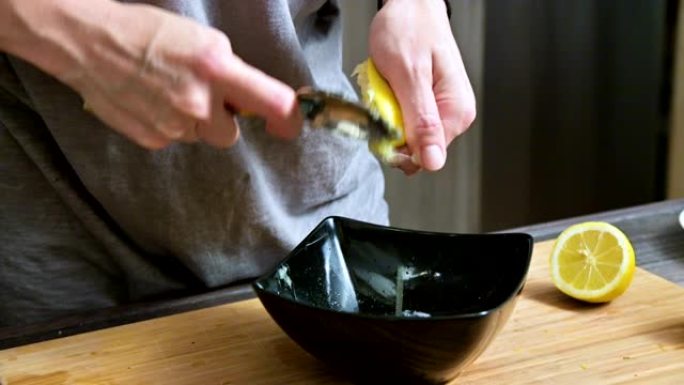 特写女孩用叉子用柠檬挤在一个黑色的碗里做酱汁