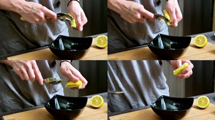 特写女孩用叉子用柠檬挤在一个黑色的碗里做酱汁