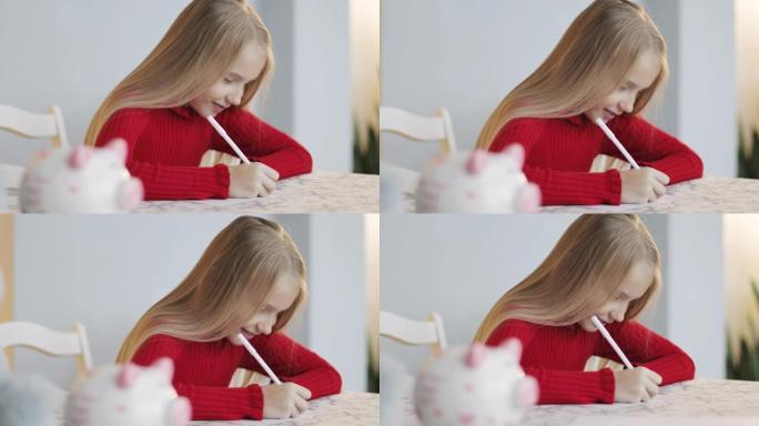 美丽可爱的女孩在节日灯光的背景下在桌子上写一封信。