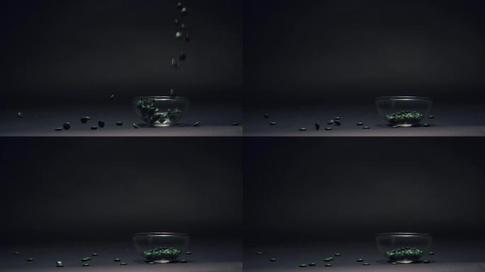 绿色糖果在慢动作的玻璃碗中掉落，黑色黑板纹理背景上的复制空间