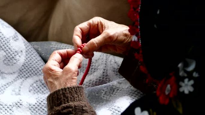 穆斯林老妇人手里拿着念珠，老妇人和念珠做礼拜，
