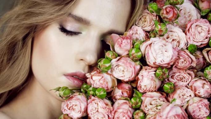 可爱的女孩，一束粉红玫瑰。美丽的女性面孔，裸妆和鲜花。情人节。在工作室里。天然化妆品。闭着眼睛。