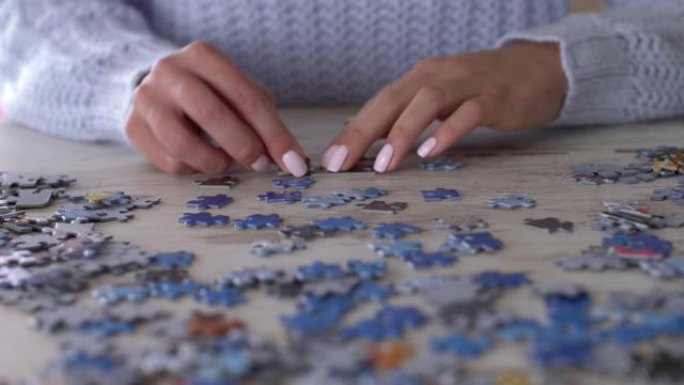 无法辨认的年轻女子用一堆碎片解决拼图的特写视频