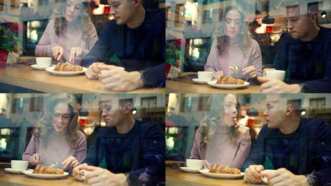 年轻漂亮的男人和女人在舒适的咖啡馆约会，一起喝咖啡和吃羊角面包