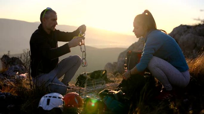 男友正在山顶训练女友，并打包攀岩设备，以便在阿尔卑斯山远足。