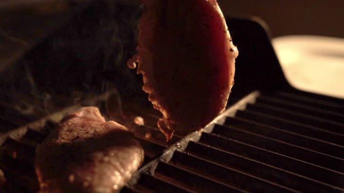晚上，户外用钳子在天井灯照亮的热烤架上翻转调味的去骨里脊肉猪排