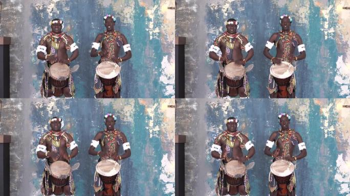 两名穿着五颜六色服装的非洲艺术家演奏djemba鼓
