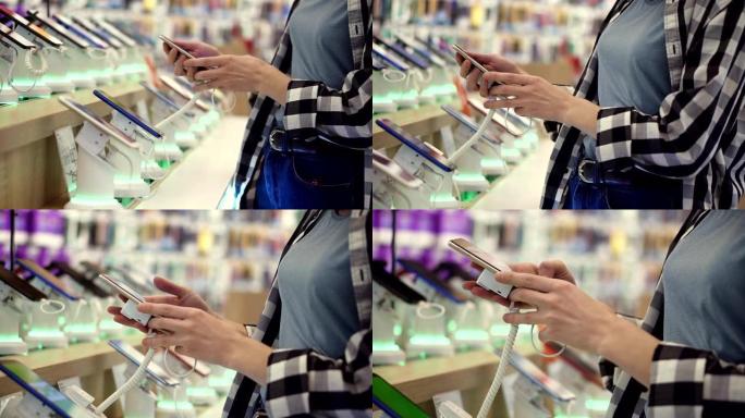 无法辨认的女人的手的腰部照片在一家电子商店选择了智能手机。她从柜台拿走智能手机并尝试使用它。侧视图
