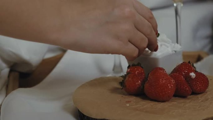 特写女性手摘草莓和奶油。