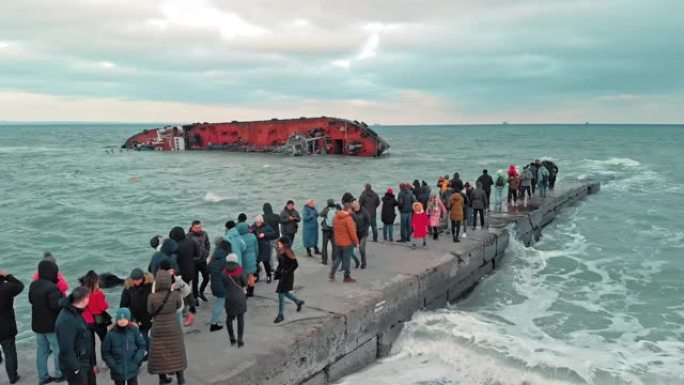 乌克兰敖德萨-2019年11月: 一场环境灾难。海滩上的许多人拍摄了一艘油轮的照片，该油轮在一场暴风