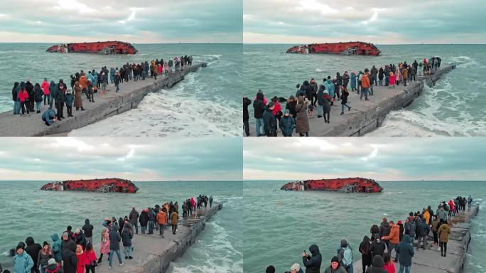 乌克兰敖德萨-2019年11月: 一场环境灾难。海滩上的许多人拍摄了一艘油轮的照片，该油轮在一场暴风