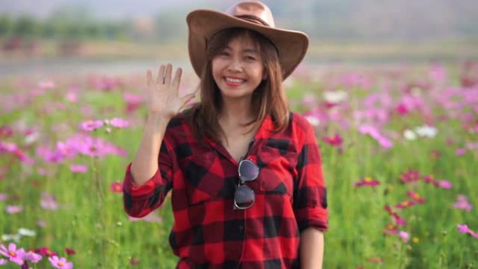 亚洲成熟女性在cosmos meadow的面部表情，招手标志