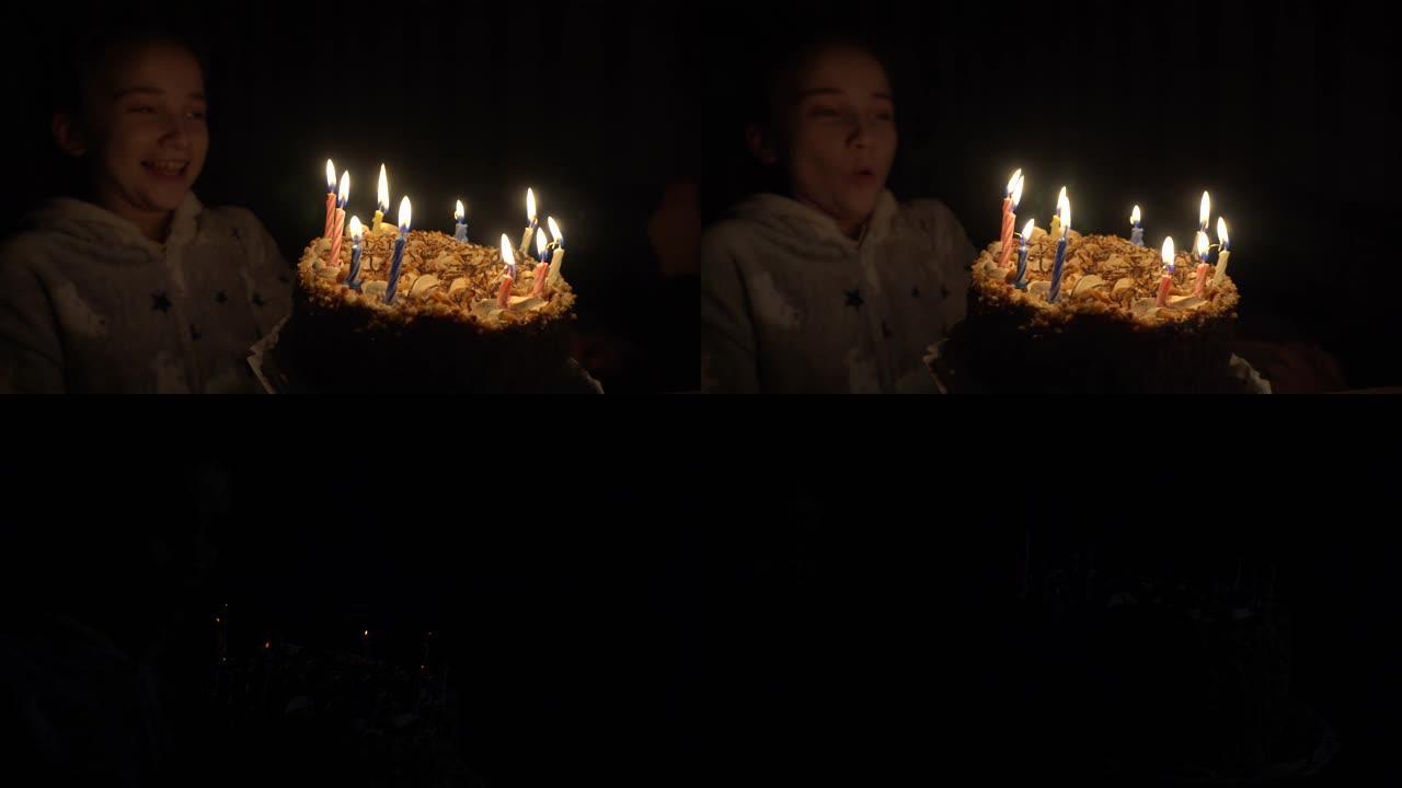 女孩庆祝生日。女孩在一个关灯的黑暗房间里熄灭了蛋糕上的所有蜡烛。烟雾流过熄灭的蜡烛。