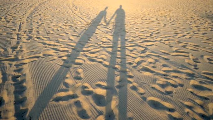 一对浪漫情侣散步和牵手度假的沙滩上的阴影