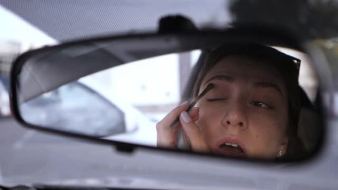 一个美丽的白人女孩看着汽车的后视镜，把她的眼睛上的阴影。17、违章在车里。一个女人聚集在交通工具上