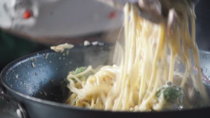 厨师在餐厅厨房的平底锅里搅拌现成的意大利面。食品成分。烹饪美食。烹饪美食。准备食物吃。美食烹饪。美味