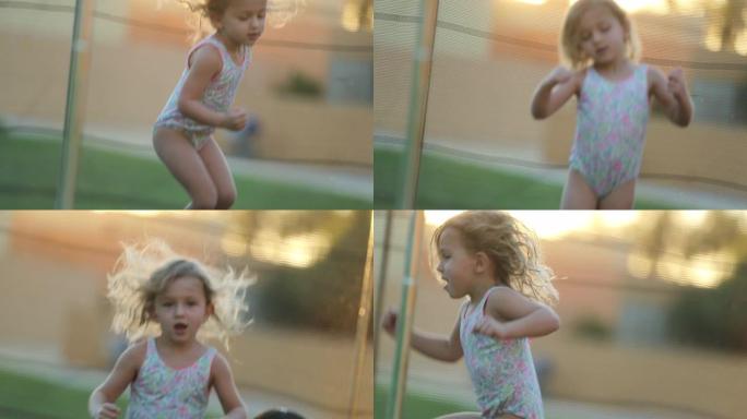 快乐的小女孩在蹦床上蹦蹦跳跳，感到快乐