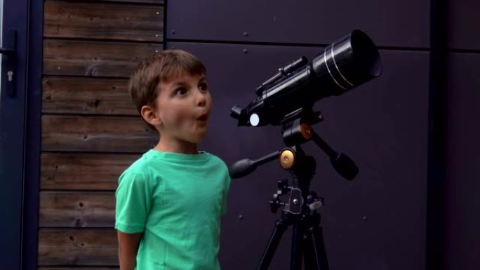开朗的小男孩通过望远镜检查天空