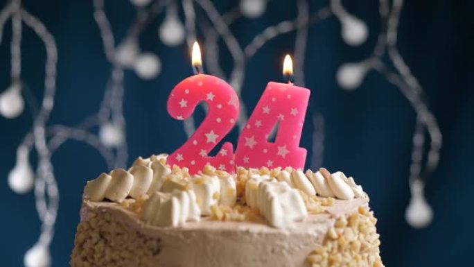 蓝色背景上有24号粉色蜡烛的生日蛋糕。蜡烛吹灭了。慢动作和特写视图