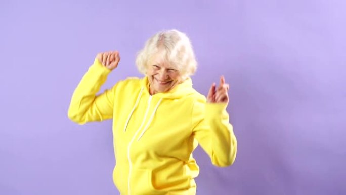 穿着黄色运动运动衫的时尚奶奶走向音乐、舞会、时尚