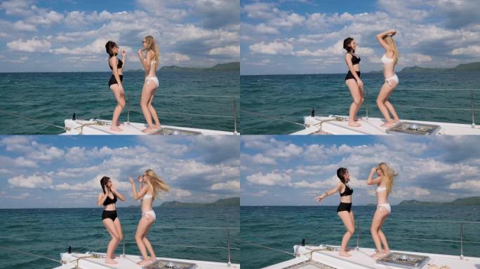 两个美丽的女孩在海上的游艇上跳舞