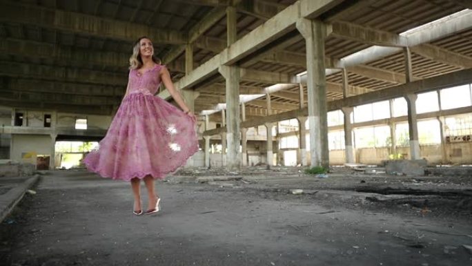 穿着粉红色连衣裙的年轻女士在废弃的仓库里