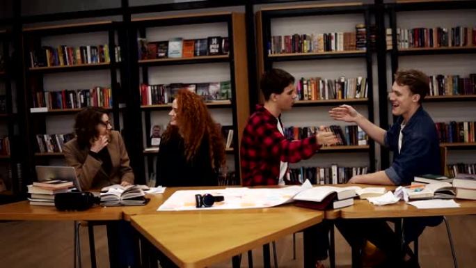 慢镜头:学生们在大学图书馆学习了几个小时后，一起玩乐。快乐和自由的学生——两个男人互相问候，打手势。