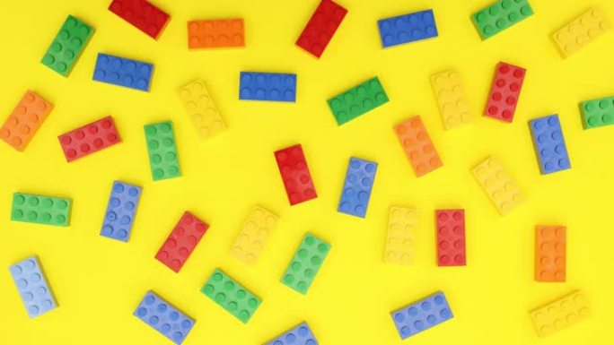 不同颜色的砖块玩具在黄色背景上移动-停止运动