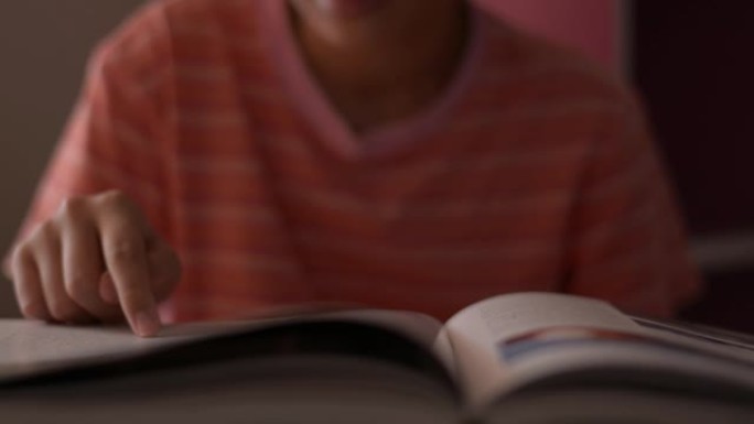 小女孩看书和翻页。女学生在阅读时沿着页面移动手指。