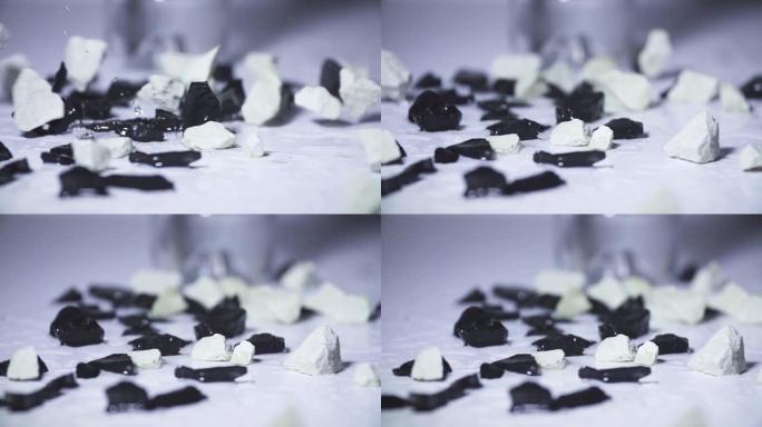石头落在白色表面上的活性炭上的慢动作