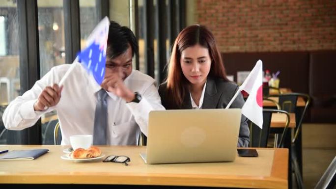 女商人和商人从笔记本电脑上观看在线体育，为日本加油打气，与英格兰挥舞旗帜和加油