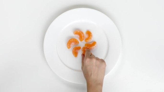 女人手从盘子里摘一块橘子