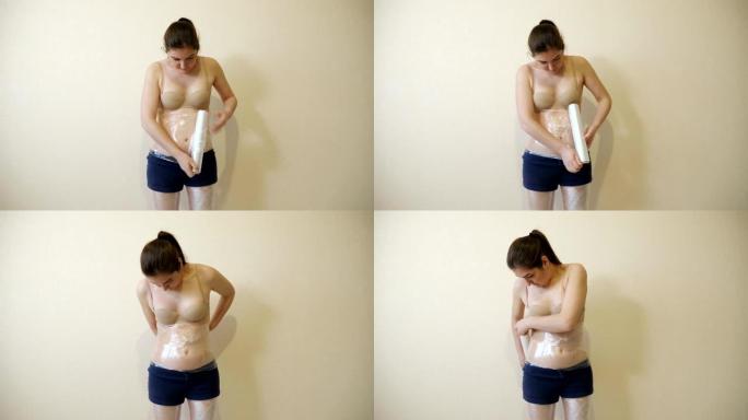 一名年轻女子用保鲜膜包裹腰部。减肥方法