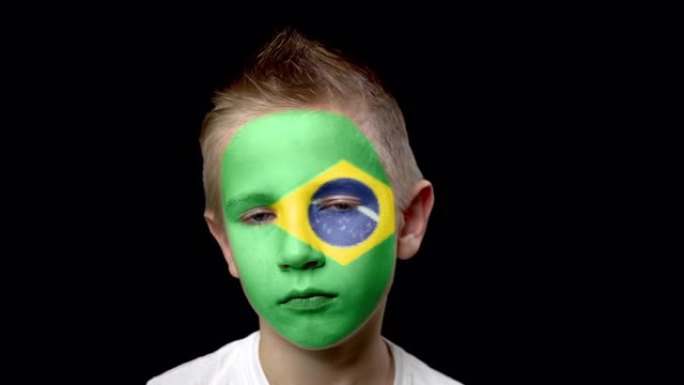 巴西足球队的悲伤球迷。一个脸上涂着民族色彩的孩子。