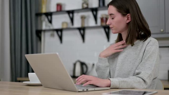 生病的年轻女子在笔记本电脑上工作并咳嗽