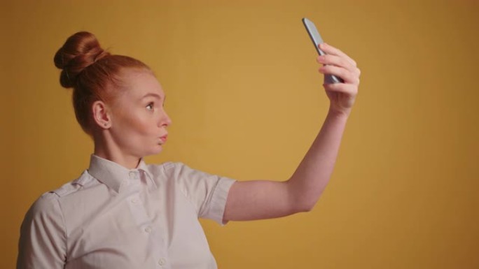有趣的红发女商人在她的智能手机慢动作中做鬼脸和自拍
