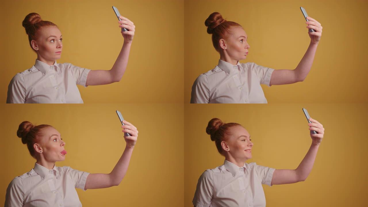 有趣的红发女商人在她的智能手机慢动作中做鬼脸和自拍