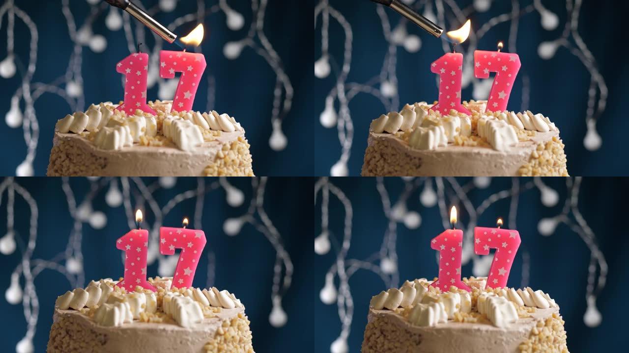 蓝色背景上有17个粉色蜡烛的生日蛋糕。蜡烛着火了。慢动作和特写视图