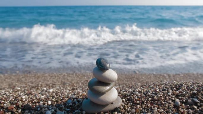 海上堆放的圆形石头。小抛光鹅卵石堆积在海滩上，蓝色光滑的海水背景