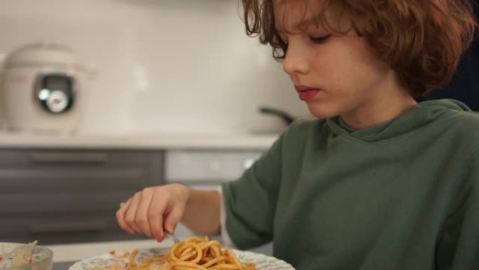 亲密肖像古怪的男孩少年在家吃午饭。小学生吃意大利面条。健康饮食，青少年饮食