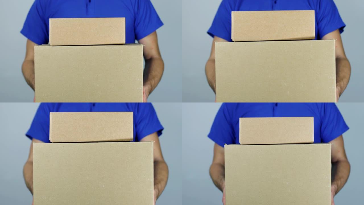 送货员在灰色背景上拿着一堆纸板箱