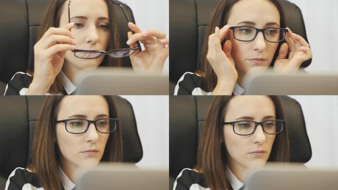 专注的女人在笔记本电脑工作前戴上眼镜。在笔记本电脑屏幕上看女性脸的特写。自信的女商人在办公桌前用笔记