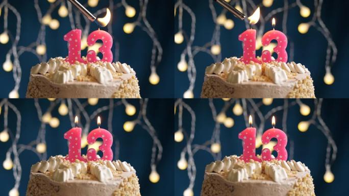 蓝色背景上有13号粉色蜡烛的生日蛋糕。蜡烛着火了。慢动作和特写视图