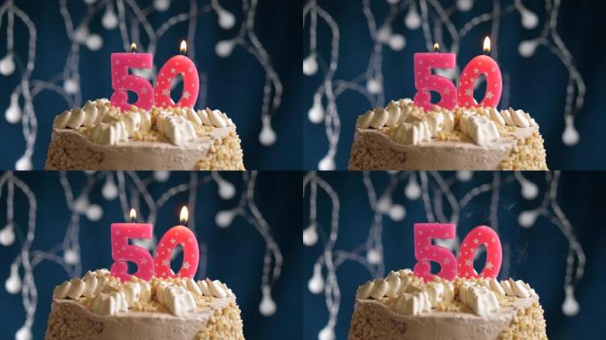 蓝色背景上有50号粉色蜡烛的生日蛋糕。蜡烛吹灭了。慢动作和特写视图
