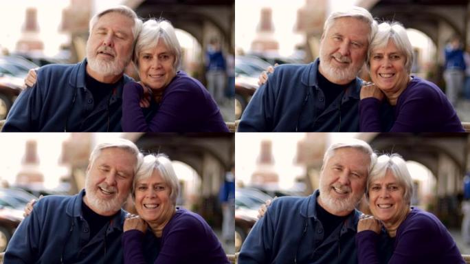 一对幸福的高级夫妇在咖啡馆外面的相机上拥抱并微笑