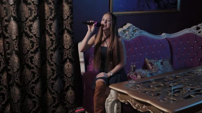 年轻女孩在卡拉ok俱乐部的沙发上对着麦克风唱歌