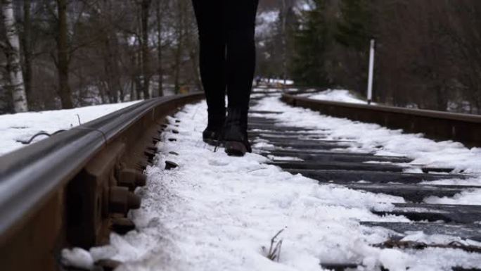 冬天，一个女孩的腿沿着旧铁轨行走。慢动作