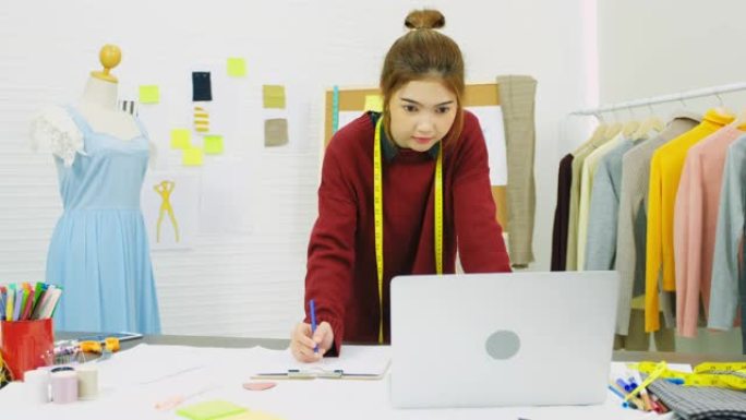 亚洲女性时装设计师在工作室工作时使用笔记本电脑，工作场所，亚洲小企业概念